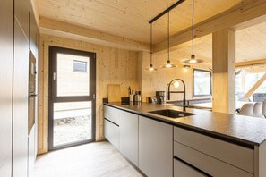 Een moderne keuken met houten wanden, een groot eiland en hanglampen.