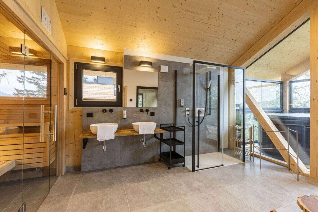 Une salle de bain moderne avec des murs en bois, une douche en verre et un banc en bois.
