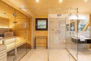 Une salle de bain moderne avec une douche à l’italienne en verre, des bancs en bois et une fenêtre visible.