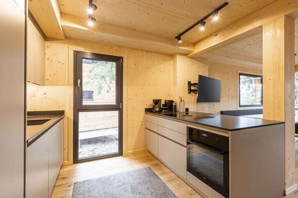 Eine moderne Küche mit Holzwänden, einem eingebauten Backofen und einem großen Fenster.