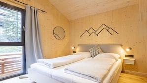 Quarto com cama, janela com cortinas e parede com desenho de montanha.