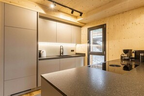Une cuisine moderne avec un plan de travail noir, des appareils en acier inoxydable et des murs en bois.