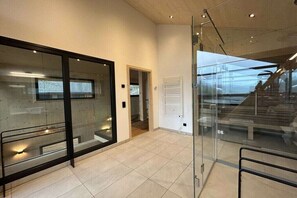 Un interior moderno con divisiones de vidrio, una escalera y piso de baldosas.