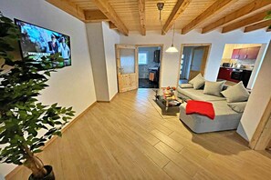 Ein Wohnzimmer mit einer Couch, einem Couchtisch und einem an der Wand befestigten Fernseher.
