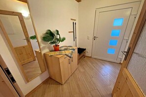 Ein Zimmer mit einem Holzschrank, einer Topfpflanze, einer Bank und einer Tür mit Milchglasfenster.