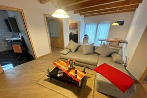 Un saló amb un sofà, una taula de centre amb un comandament a distància i una manta vermella.