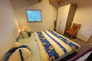 Ein Schlafzimmer mit Bett, Fenster, Kleiderschrank und Stuhl.