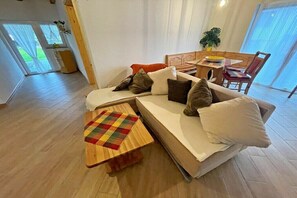 A living room with a sofa, a wooden coffee table, and a dining area with a table and chairs. - Holiday apartment with 1 bedroom (Zirchow)