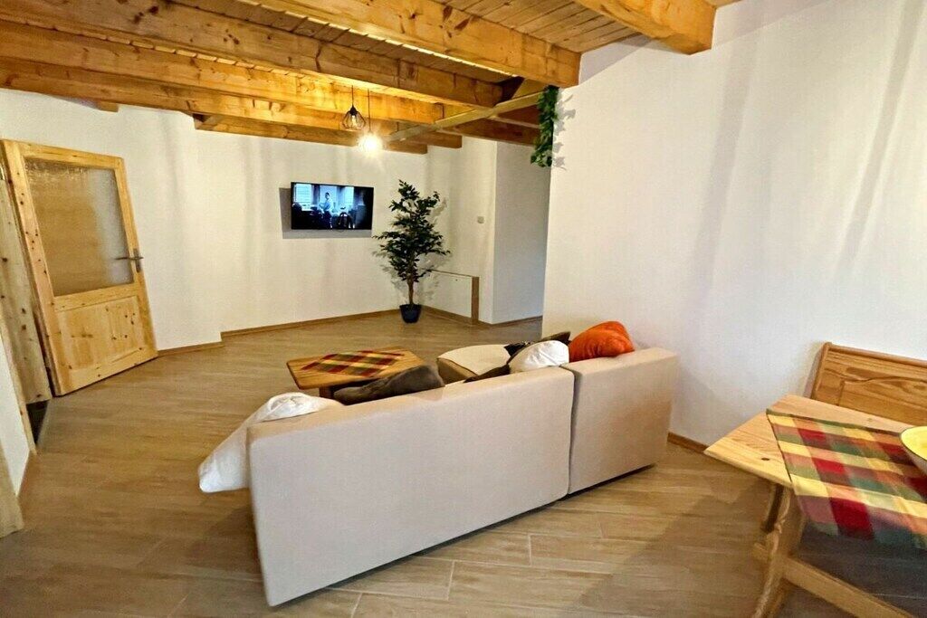 A cozy living area with a sofa, a television, and a wooden ceiling.