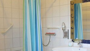 Ein Badezimmer mit einem weißen Waschbecken, einem Spiegel mit Zierrahmen, einer Duschvorhang und einem Handtuchhalter.