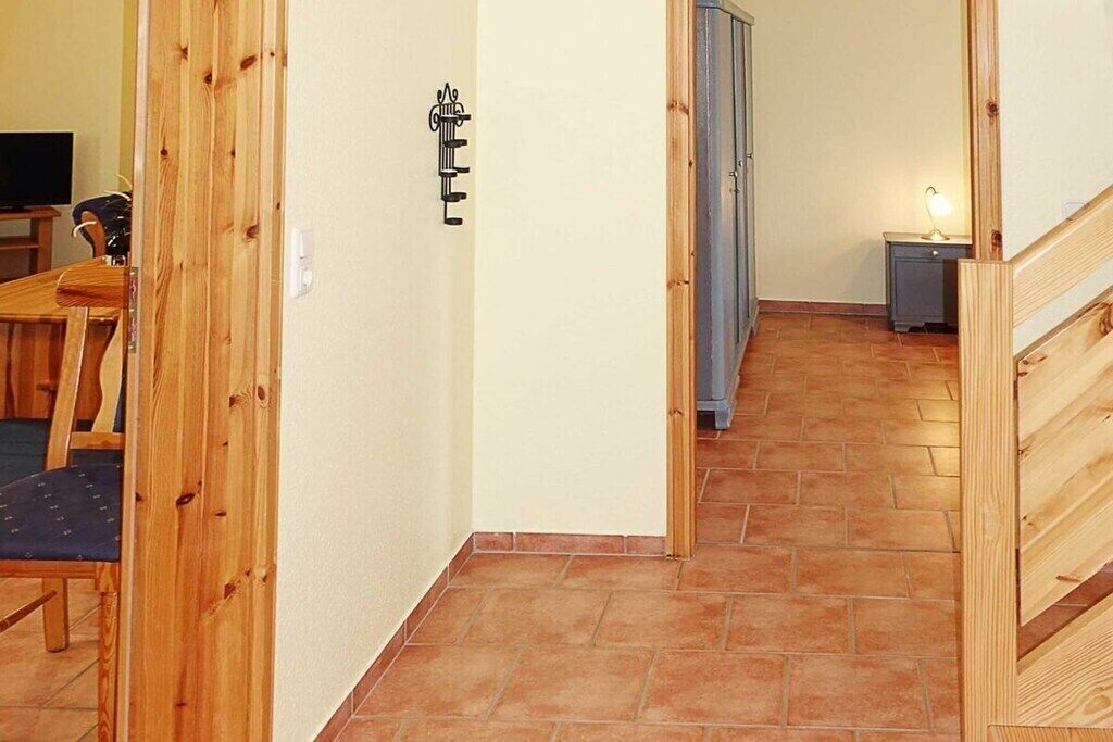 A hallway with wooden flooring, a door, and a small table with a lamp.