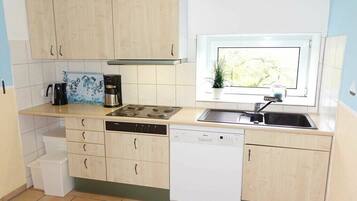 Cozinha compacta com máquina de lavar louça, fogão e pia.