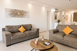A modern living room with two grey sofas, a wooden coffee table, and a decorative wall piece. - Comfort & Modern Sea-view 3 bdr Apart (St. Paul's Bay)