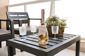 A bottle of champagne on a table with two glasses, a potted plant, and a chair. - Comfort & Modern Sea-view 3 bdr Apart (St. Paul's Bay)