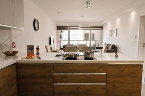Een moderne keuken met een centraal eiland, houten kastjes en een zithoek met een bank en stoelen.