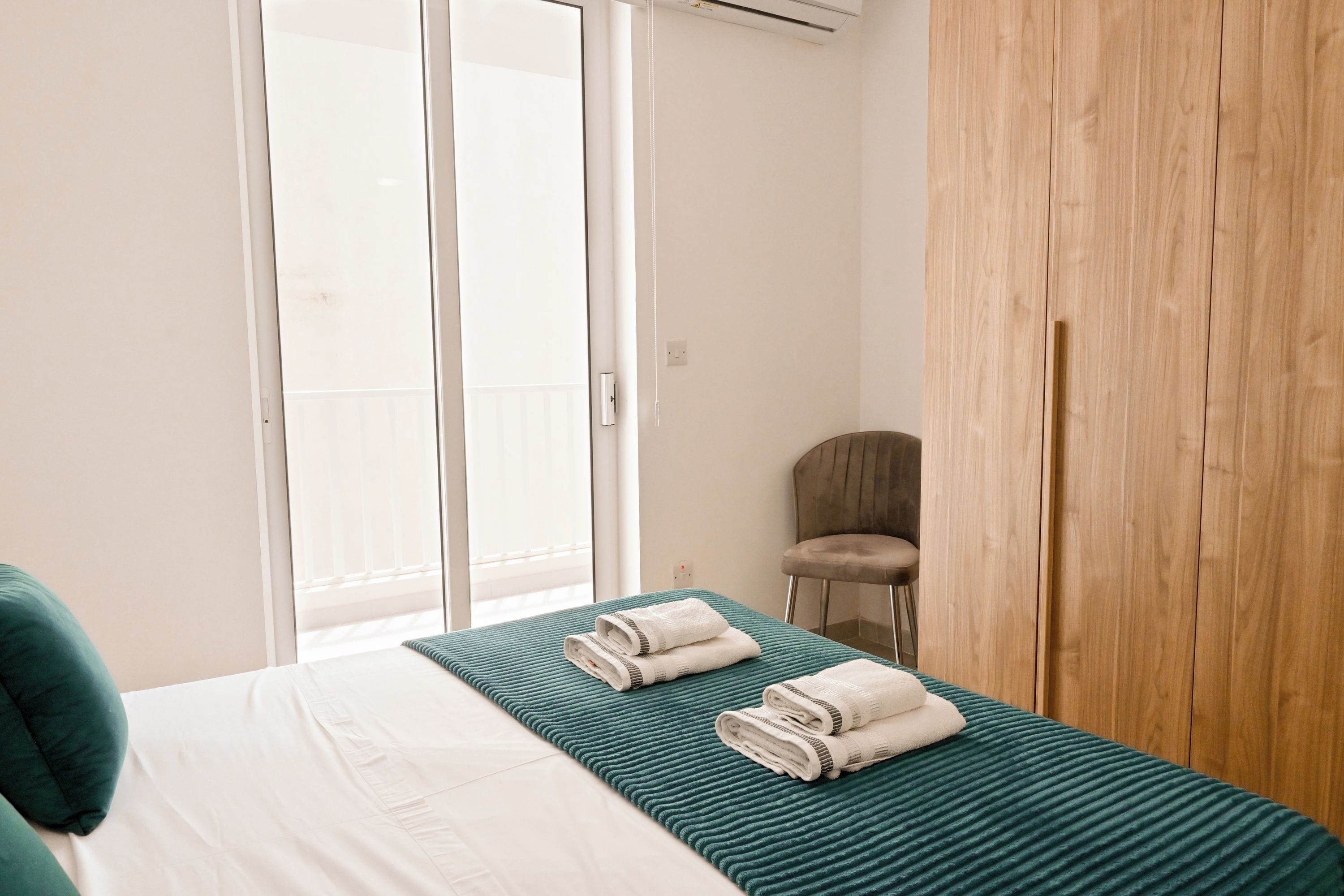 Une chambre d’hôtel avec un lit, une chaise et une armoire en bois.