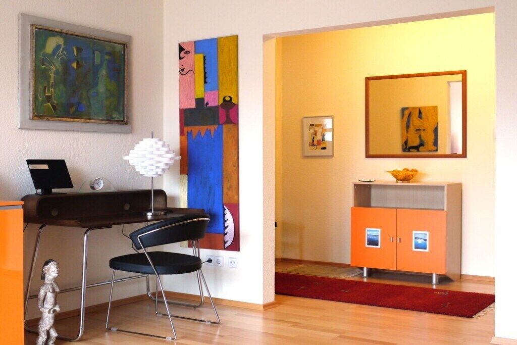 A room with a desk, chair, and a large abstract painting on the wall.