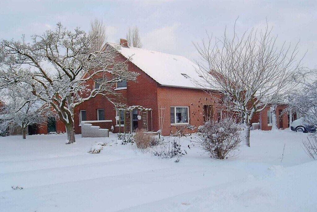 Ein rotes Backsteinhaus mit schneebedecktem Dach und Garage.