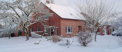 A red brick house with a snow-covered roof and a garage.