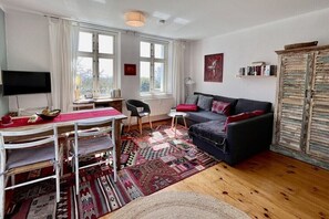 Un salon meublé comprenant un canapé, une table à manger avec des chaises, un téléviseur et une bibliothèque.