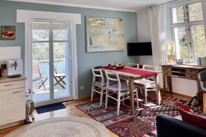 A room with a dining table, chairs, a TV, and a window. - Holiday apartment with 1 bedroom (Göhren)