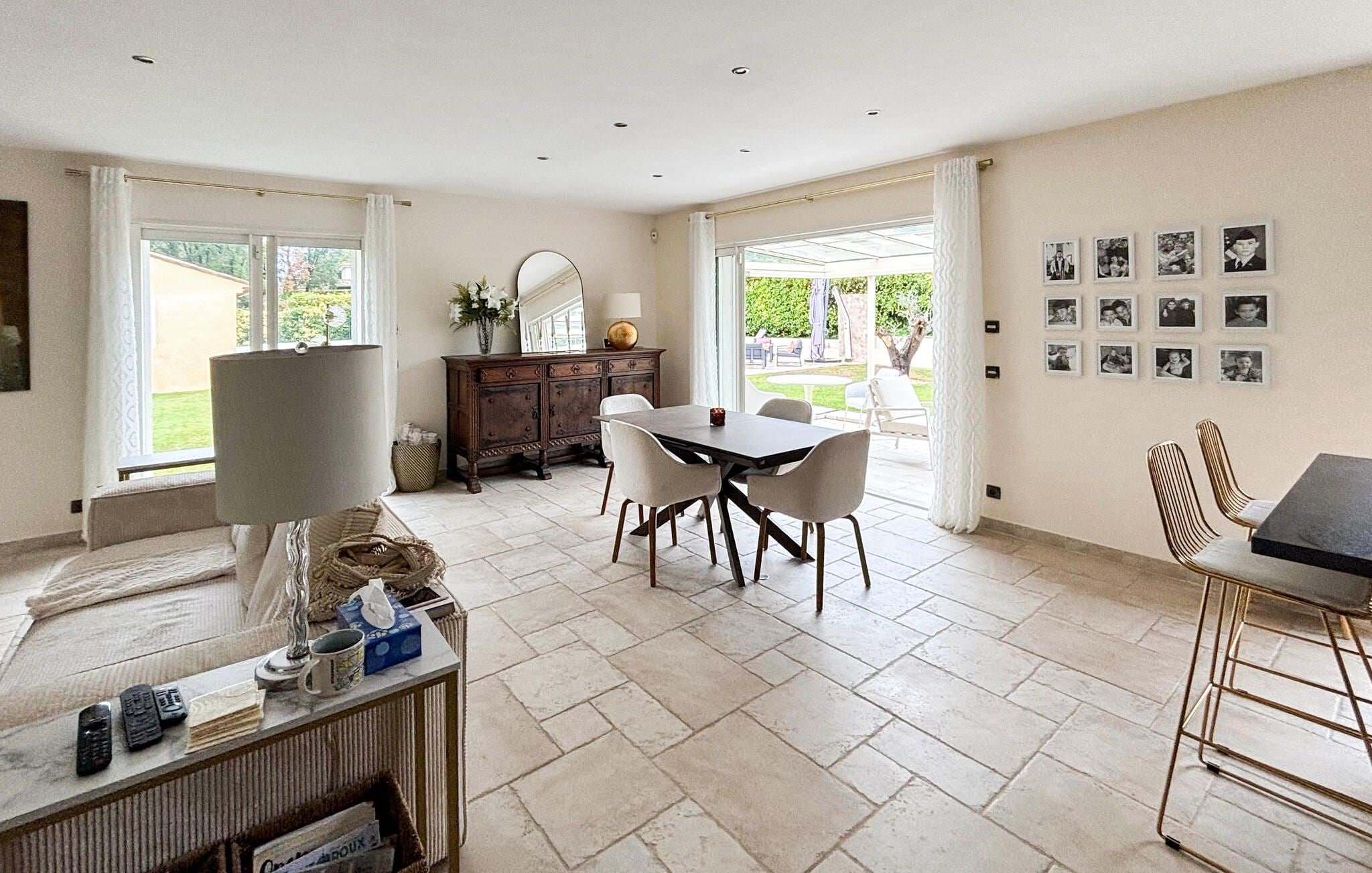 A spacious room with a dining table, chairs, a cabinet, and a large window.