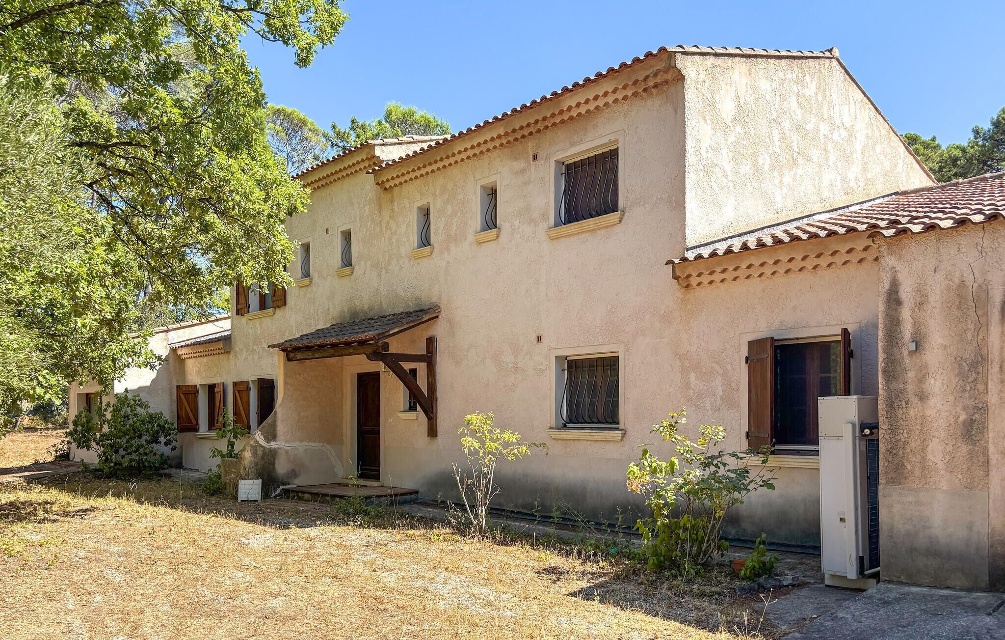 A two-story building with a tiled roof, a wooden porch, and a small garden area.
