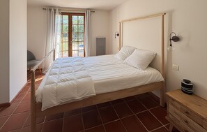 A bedroom with a large bed, a chair, a wooden dresser, and a window with curtains. - Cozy home in Besse sur Issole (Besse sur Issole)
