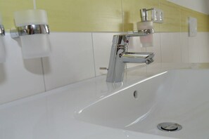 Ein Waschbecken mit einem Chromarmaturen und einer weißen Arbeitsplatte.