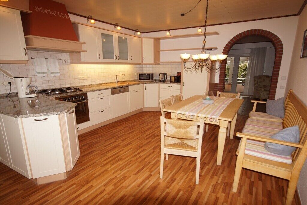 A kitchen with a dining area, wooden flooring, and a brick archway.