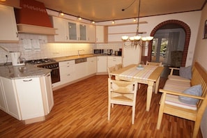 A kitchen with a dining area, wooden flooring, and a brick archway. - Holiday apartment with 2 bedrooms (Osteel)
