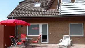 A patio with a table, chairs, and a sun umbrella. - Crab, holiday home Diana (Krummhörn \/ OT Greetsiel)