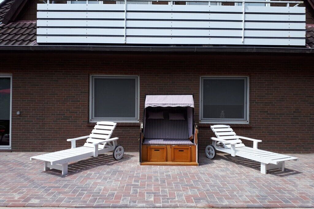 Un bâtiment à la façade en briques, doté de deux grandes fenêtres et d’un espace extérieur abrité avec un banc et une table.