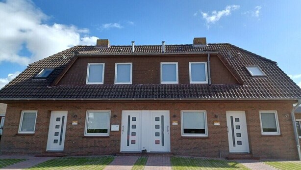 A two-story brick building with a tiled roof, a central entrance with a door, and a small window on the upper floor. - Crab, holiday home Diana (Krummhörn \/ OT Greetsiel)