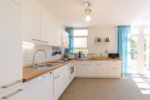 Eine moderne Küche mit weißen Schränken, einer Holz Arbeitsplatte und einem eingebauten Geschirrspüler.