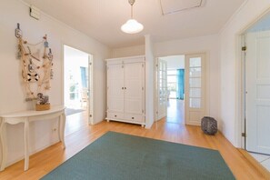 Ein Zimmer mit Holzboden, weißen Wänden, einem grünen Teppich, einem weißen Schrank und einer Wanddekoration.