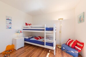 Ein Schlafraum mit Etagenbett, Schreibtisch, Lampe und einer kleinen Aufbewahrungsbox.