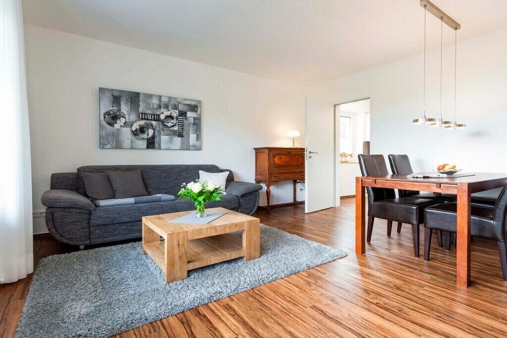 A living room with a sofa, coffee table, and dining area with chairs and a table.