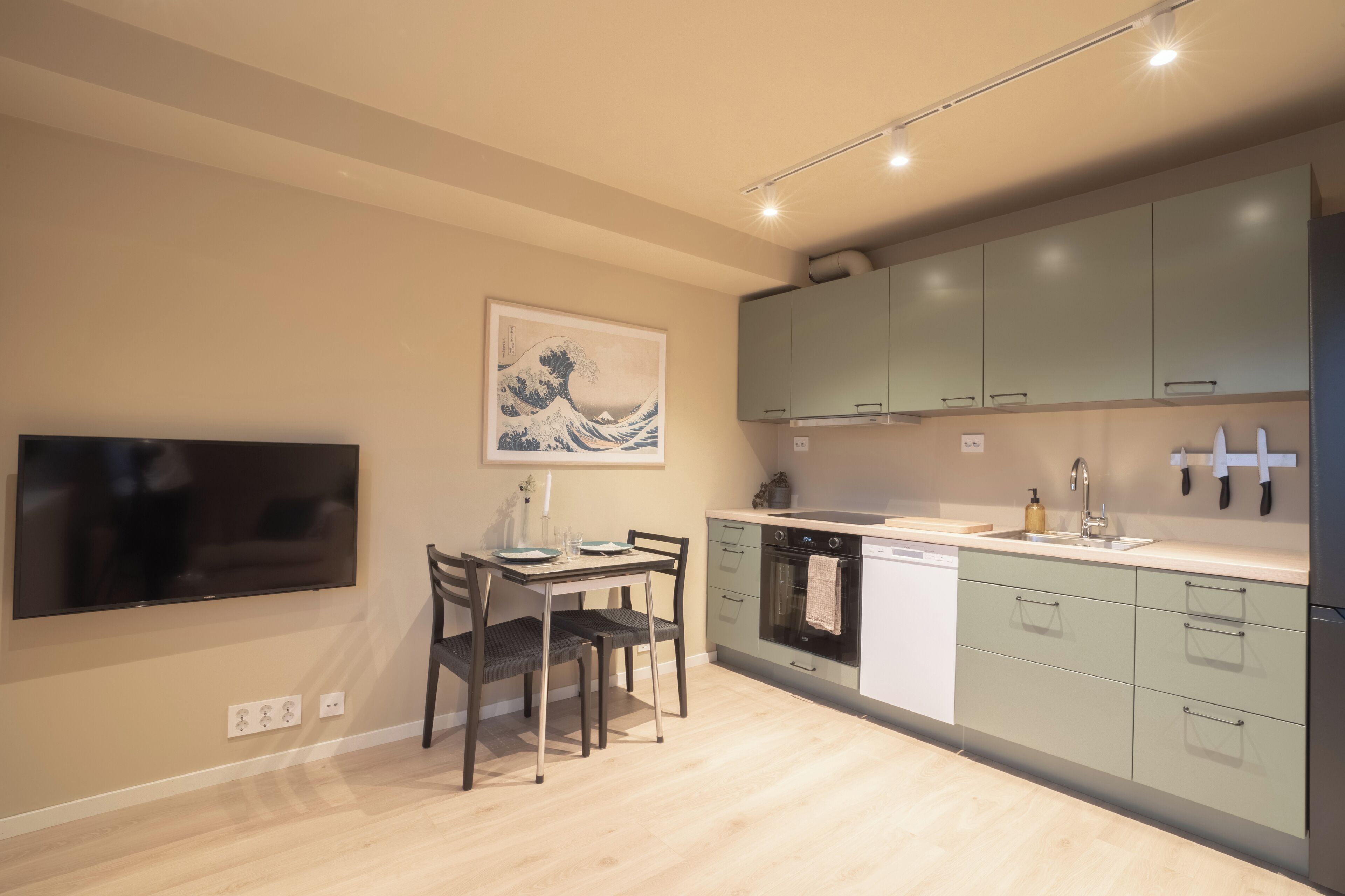 Cocina moderna con comedor, que incluye un televisor de pantalla plana, un cuadro y un lavamanos con electrodomésticos contemporáneos.