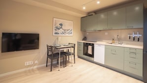 Cocina moderna con comedor, que incluye un televisor de pantalla plana, un cuadro y un lavamanos con electrodomésticos contemporáneos.