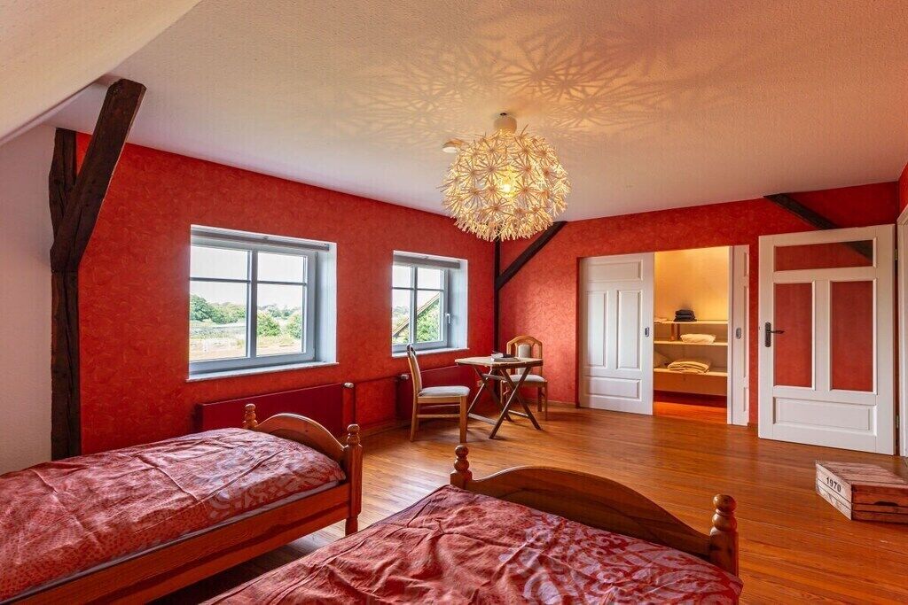 A room with two beds, a dining table, and a chandelier.
