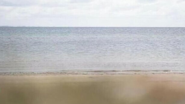 Ein Strand mit blauem Himmel und ruhiger See.