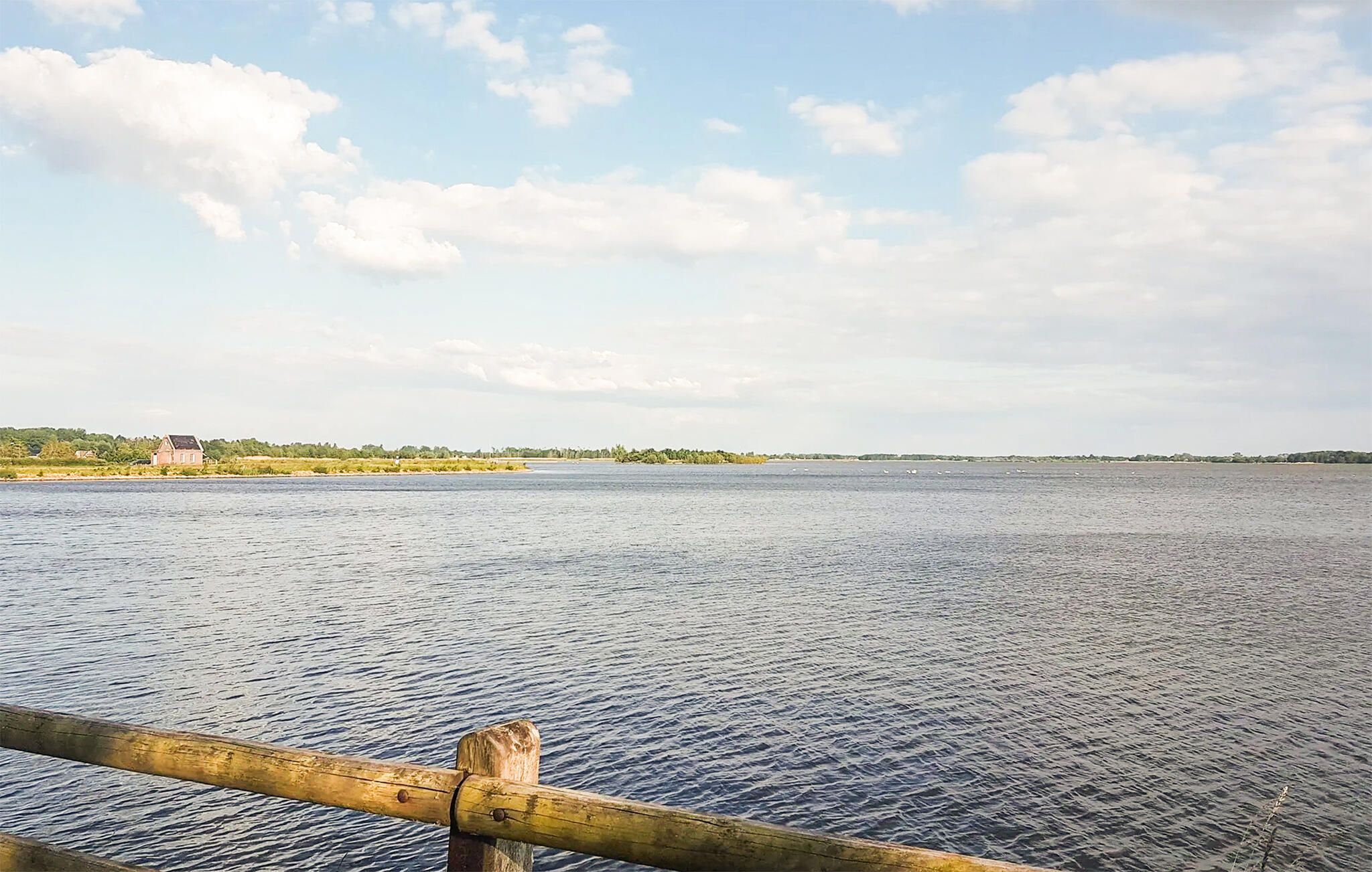 A calm body of water with a wooden railing in the foreground.