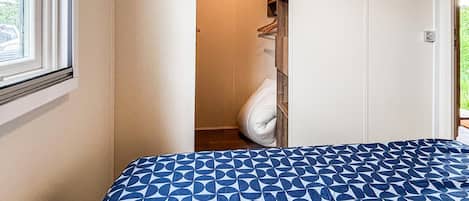 A bedroom with a bed, a closet, and a window.