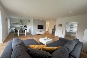 Ein modernes Wohnzimmer mit einem grauen Sofa, einem Couchtisch und einem Fernseher.