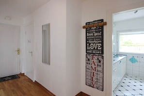 A hallway with a door, a mirror, and a wall with motivational quotes. - Holiday home with 1 bedroom (Scharbeutz)