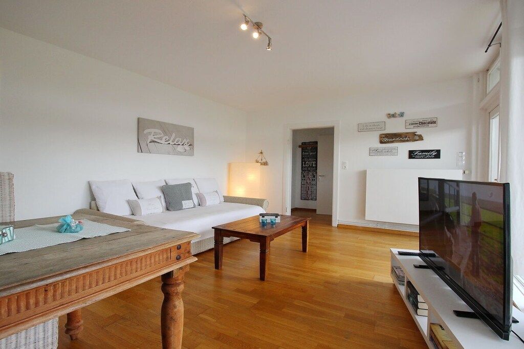 A living room with a sofa, coffee table, TV, and wall decorations.