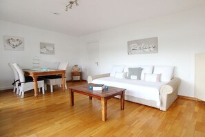 Ein gemütliches Wohnzimmer mit einer Couch, einem Couchtisch und einem Essbereich mit Stühlen und einem Tisch.