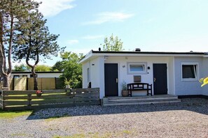 A single-story building with a dark front door, a small window, and a number '11' on the wall. - Holiday home with 1 bedroom (Scharbeutz)