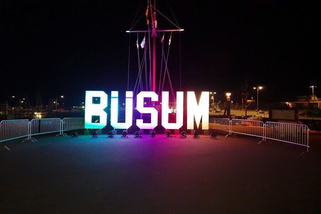 A nighttime view of a large illuminated sign with the word 'BUSUM' in capital letters.